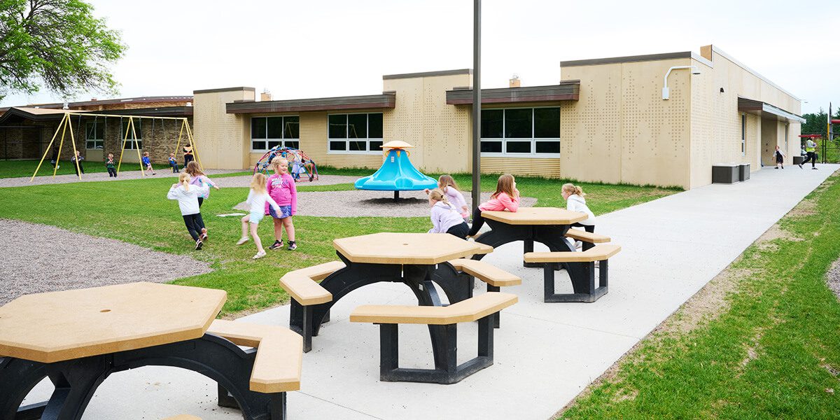 Kids sitting at outdoor tables on playground